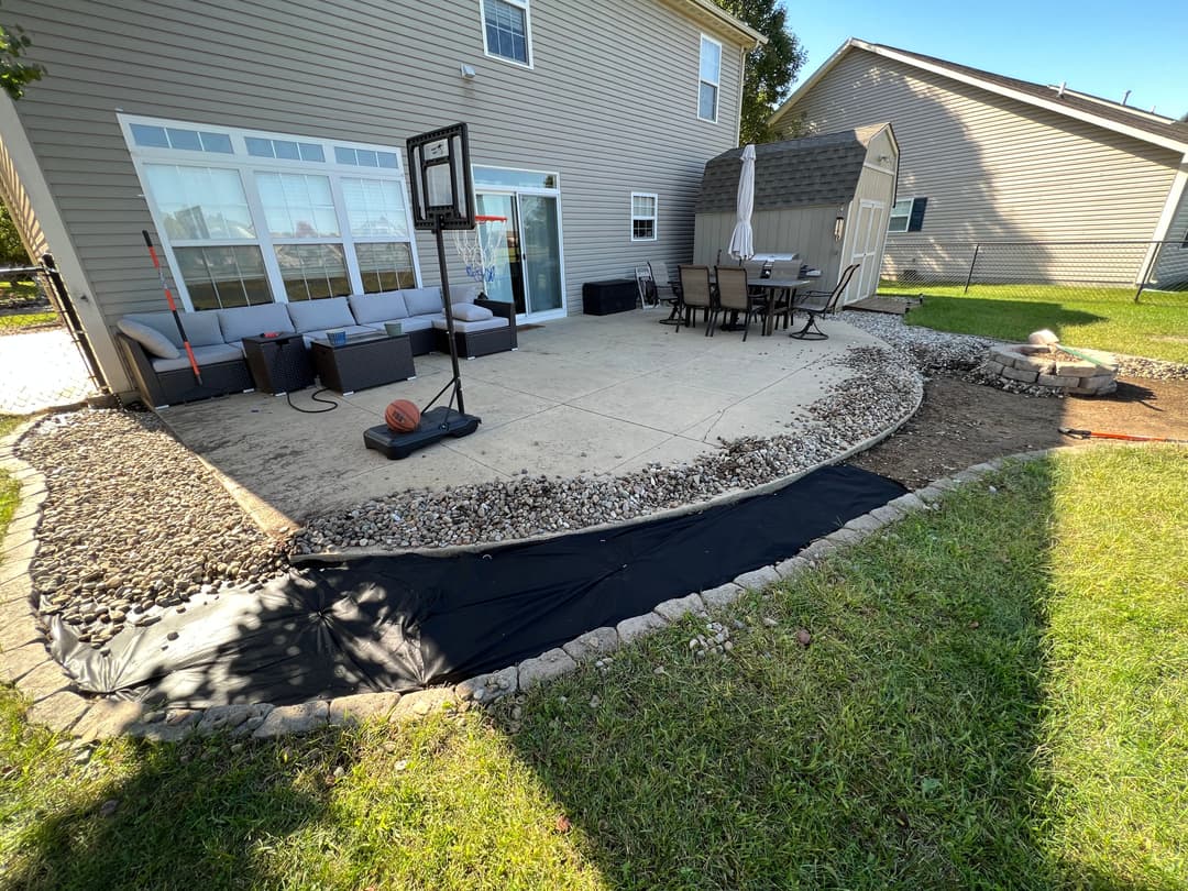 Backyard with patio area, basketball hoop, seating, and garden landscaping elements.