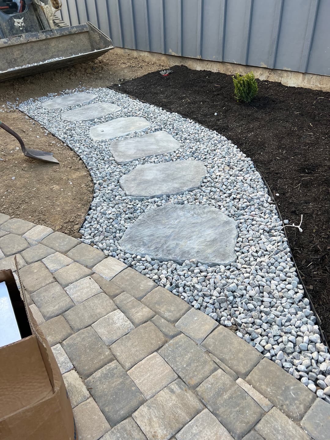 Stone pathway with gravel borders leading through landscaped yard.