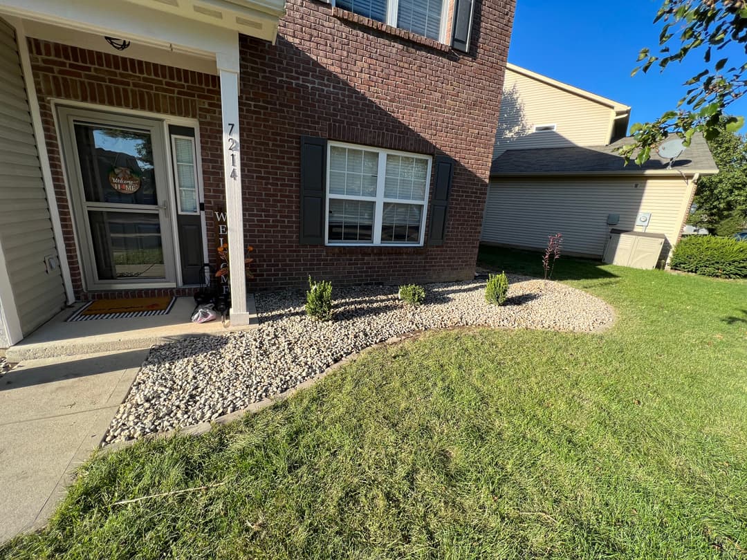 Landscaped front yard with gravel, shrubs, and a brick house at 7224.