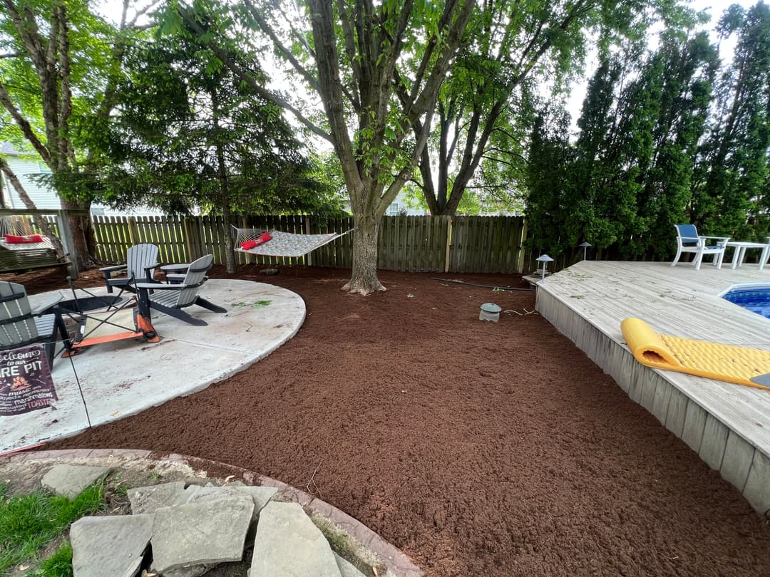 Mulched backyard space with a tree, patio area, and outdoor seating.