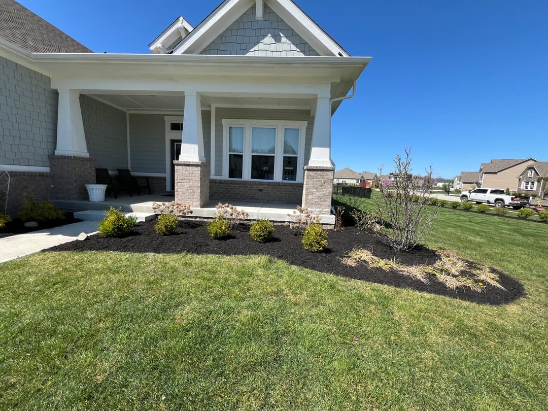 Front porch of a modern home with landscaped garden and clear blue sky.