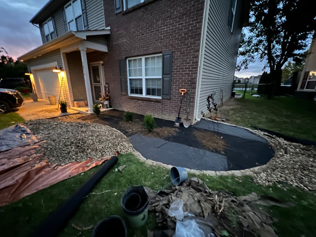 Home exterior with new landscaping, including gravel and plants, during evening twilight.