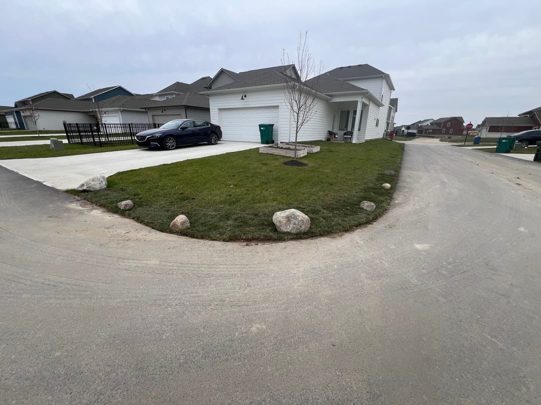 White house with garage on a curved driveway, green lawn, and parked car.