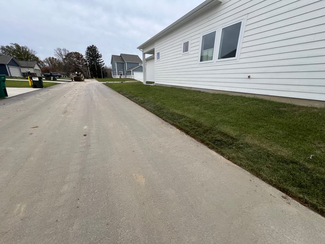 Newly paved driveway alongside a well-manicured lawn and residential homes.